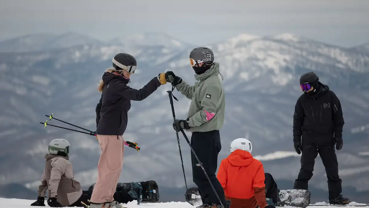 SAS Niseko instructor celebrating with a lesson group on the mountain